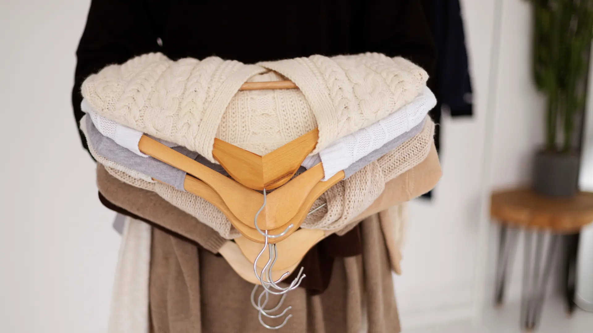 wanita memegang tumpukan atasan sambil berdiri (capsule wardrobe)